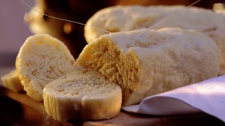 Serviettenknödel werden mit Bindfaden in Scheiben geschnitten.