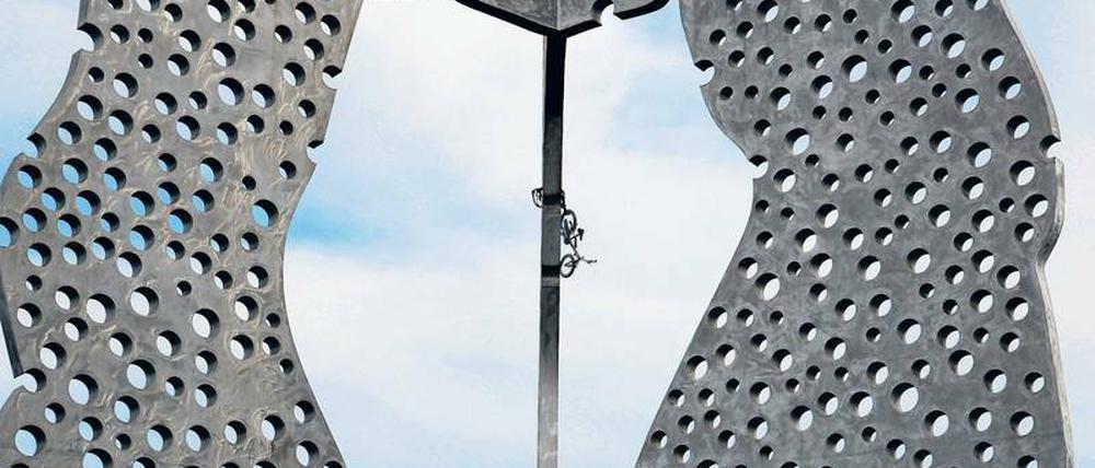 „Hochgeradelt, angeschlossen“. Die Spekulationen, wie das Fahrrad auf den „Molecule Man“ kam, sind wortreich und zahlreich. Nur das „Warum?“ scheint niemanden zu interessieren.