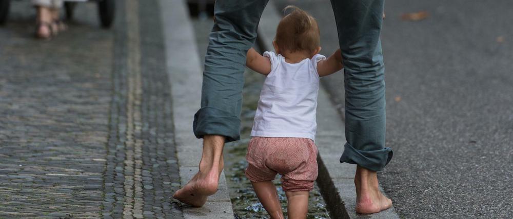 Ein Vater erfrischt sich mit seiner kleinen Tochter in Freiburg im Wasser.