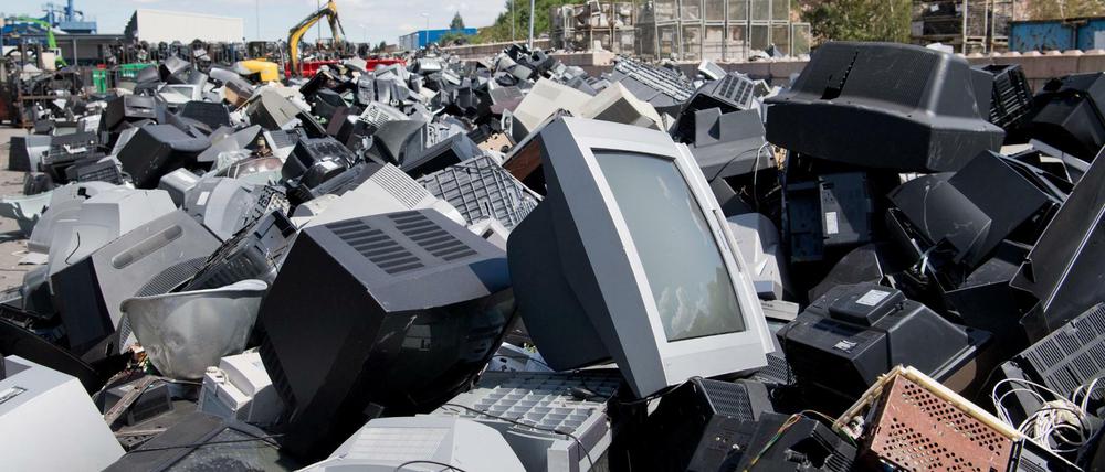 Ausgediente Elektrogeräte, Fernseher und Computerbildschirme auf einem Firmenhof.