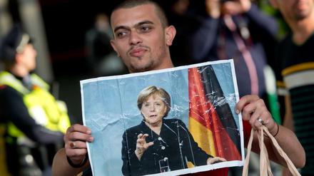 Ein Flüchtling hält am 05.09.2015 auf dem Hauptbahnhof in München ein Foto von Angela Merkel in den Händen.