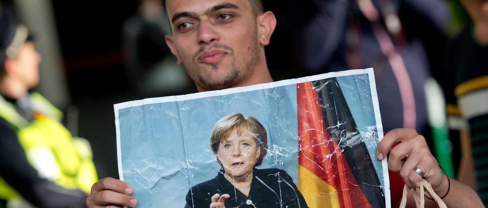 Ein Flüchtling hält am 05.09.2015 auf dem Hauptbahnhof in München ein Foto von Angela Merkel in den Händen.