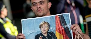 Ein Flüchtling hält am 05.09.2015 auf dem Hauptbahnhof in München ein Foto von Angela Merkel in den Händen. 