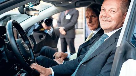 Partner. Olaf Scholz sitzt am Steuer eines Audi, VW-Chef Müller schaut zu.