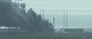 Eine dichte schwarze Rauchsäule steht über Cape Canaveral.