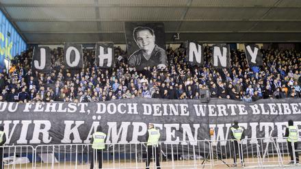 Darmstädter Fans halten vor Spielbeginn ein Foto und ein großes Transparent in die Höhe für den verstorbenen Lilien-Fan Jonathan "Johnny" Heimes. (Archiv)