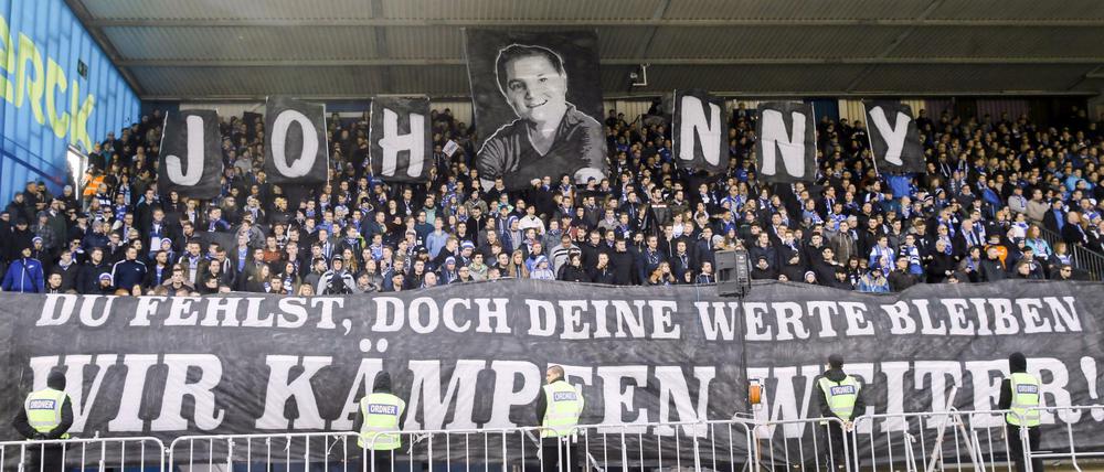 Darmstädter Fans halten vor Spielbeginn ein Foto und ein großes Transparent in die Höhe für den verstorbenen Lilien-Fan Jonathan "Johnny" Heimes. (Archiv)