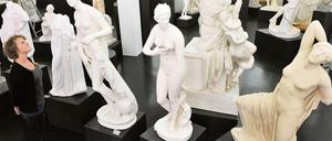 Eine Frau betrachtet Gipsabgüsse von antiken Statuen.