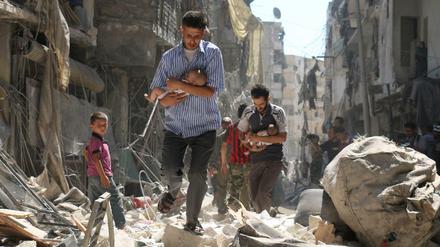 Die syrische Zivilbevölkerung leidet am meisten unter den beständigen Angriffen. Hier versuchen Männer in der von Ruinen geprägten nördlichen City von Aleppo, Babys vor den Luftangriffen in Sicherheit zu bringen. 
