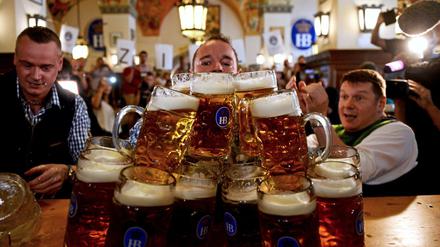 Der Münchner Matthias Völkl (M) trägt am 12.09.2016 im Hofbräuhaus in München (Bayern) 29 Maßkrüge über einen 40 Meter langen Gang.