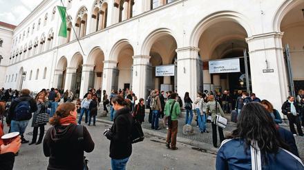 Studierende stehen vor einem Hochschulgebäude.