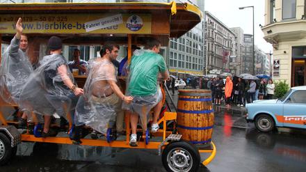 Berlin-Touristen auf dem Bierbike beim Sightseeing am Checkpoint Charlie an der Friedrichstraße in Berlin.