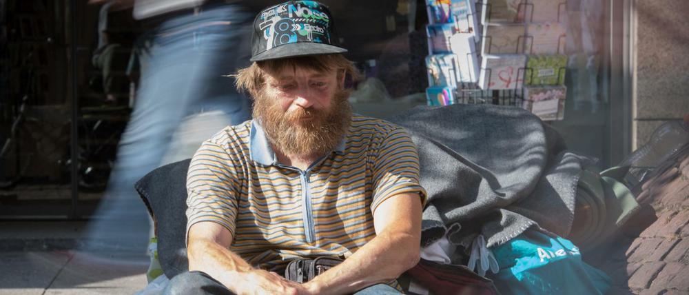 Der als "Eisenbahn-Reiner" in der Frankfurter Obdachlosen-Szene bekannte Reiner Schaad sitzt auf seinem Stammplatz in der Innenstadt von Frankfurt am Main (Hessen), während Passanten an ihm vorbei hetzen.