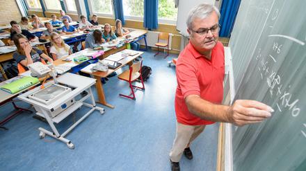 Ein Lehrer steht an einer Wandtafel und schreibt Formeln an.