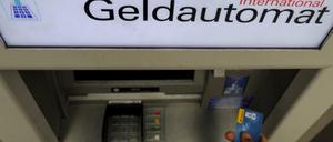 Ein Bankkunde hebt mit seiner Girokarte Bargeld von einem Geldautomaten ab.