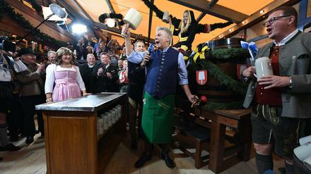 Der Münchner Oberbürgermeister Dieter Reiter (Mitte, SPD) sticht das erste Wiesn-Fass an. 