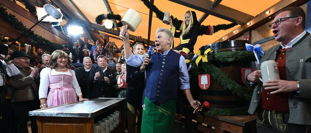 Der Münchner Oberbürgermeister Dieter Reiter (Mitte, SPD) sticht das erste Wiesn-Fass an.