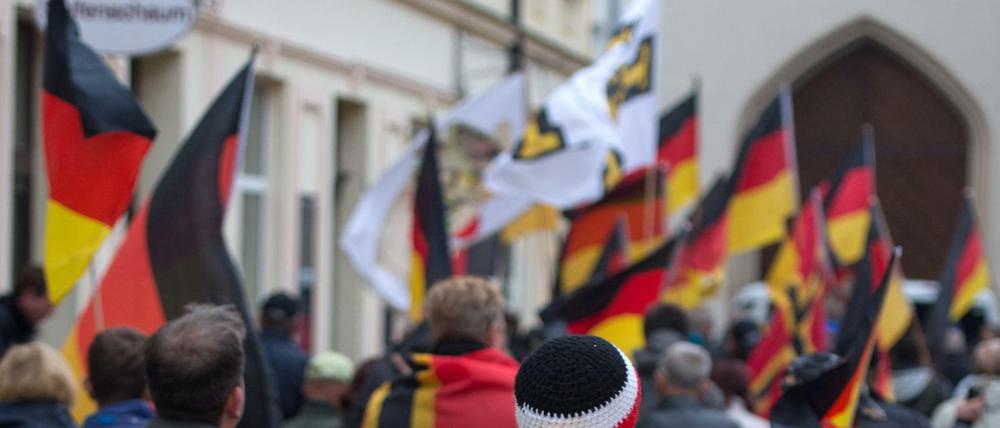 Ein Mann hat eine Fahne mit Logo der Identitären Bewegung geht im Rahmen einer Kundgebung vom Kornmarkt in Bautzen (Sachsen) durch die Innenstadt.