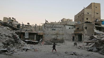 Ein Junge steht in Aleppo zwischen zerbombten Wohnhäusern.