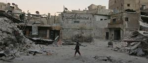 Ein Junge steht in Aleppo zwischen zerbombten Wohnhäusern.