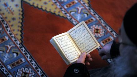 Ein Mann hält einen Koran in der Hand.