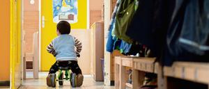 Ein Junge fährt in einer Kindertagesstätte mit einem Pukylino an einem Garderobenständer vorbei. 