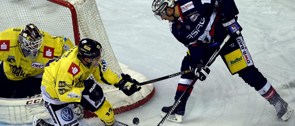Spencer Machacek (r) von den Eisbären Berlin und Torwart Niklas Treutle (l) und Mike Collins von den Krefeld Pinguinen kämpfen um den Puck.