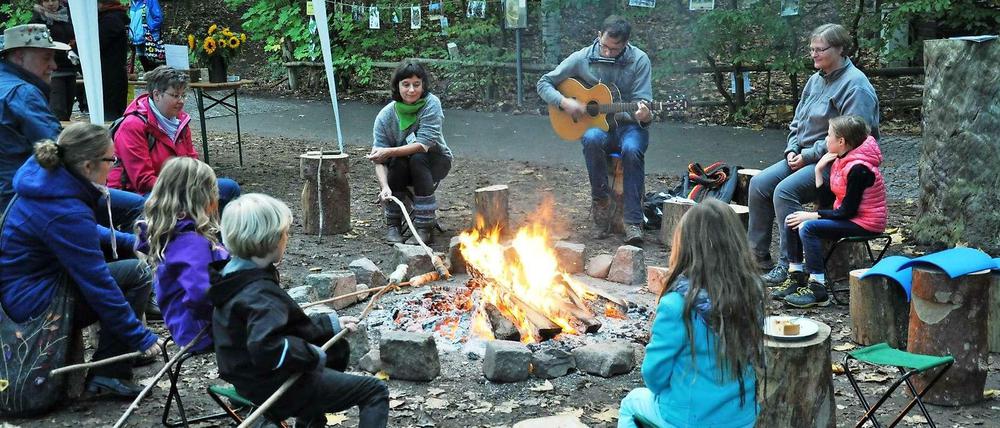 Gundula Stamm und Elke Sobota-Baisch (links und rechts vom Musikanten) mit Kids am Lagerfeuer.