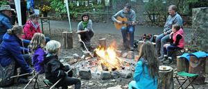 Gundula Stamm und Elke Sobota-Baisch (links und rechts vom Musikanten) mit Kids am Lagerfeuer.