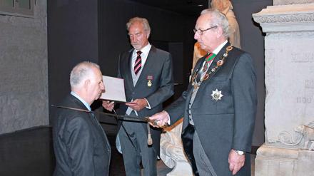 Assistiert von Karl-Heinz Meyer (Mitte) schlägt Prinz Eduard den Arzt Gerd Scharfenberg zum Ritter.