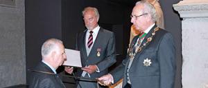 Assistiert von Karl-Heinz Meyer (Mitte) schlägt Prinz Eduard den Arzt Gerd Scharfenberg zum Ritter.
