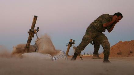 A Fighter from the Free Syrian Army covers his ears as he fires a mortar launcher during fighting against the Islamic State (IS) group jihadists on the outskirts of the northern Syrian town of Dabiq, on October 15, 2016.Turkish-backed Syrian rebels captured the northern town of Dabiq from the Islamic State group on October 16, a monitoring group and rebels said. Dabiq holds crucial ideological importance for IS because of a Sunni prophecy that states it will be the site of an end-of-times battle between Christian forces and Muslims. / AFP PHOTO / Nazeer al-Khatib