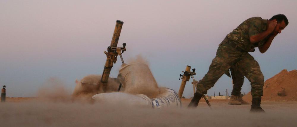 A Fighter from the Free Syrian Army covers his ears as he fires a mortar launcher during fighting against the Islamic State (IS) group jihadists on the outskirts of the northern Syrian town of Dabiq, on October 15, 2016.Turkish-backed Syrian rebels captured the northern town of Dabiq from the Islamic State group on October 16, a monitoring group and rebels said. Dabiq holds crucial ideological importance for IS because of a Sunni prophecy that states it will be the site of an end-of-times battle between Christian forces and Muslims. / AFP PHOTO / Nazeer al-Khatib