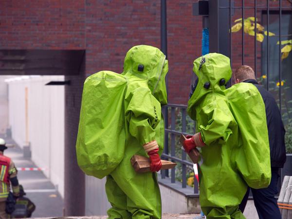 Einsatzkräfte der Feuerwehr in Schutzanzügen gehen in Berlin auf das Gelände der in Bau befindlichen Zentrale des Bundesnachrichtendienstes (BND).