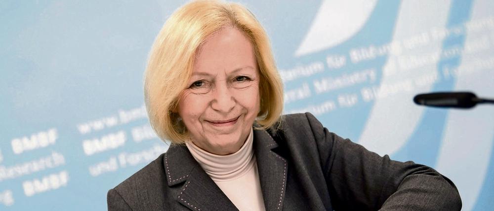 Eine Frau lächelt in die Kamera und hantiert mit ihrer Handtasche.