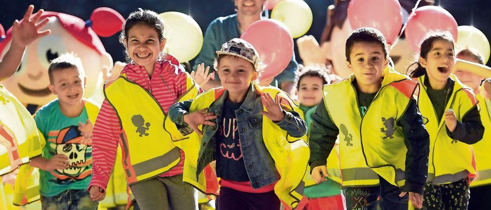 Kinder in gelben Rettungswesten laufen lachend in Richtung Kamera.