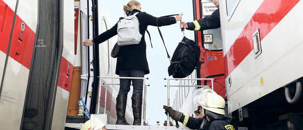 Zug um Zug. Auf diesem Bild sieht man Feuerwehrleute, die Passagieren eines liegen gebliebenen ICEs helfen, in einen Intercity zu steigen.