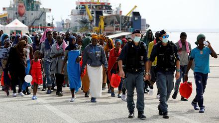 Italienische Polizisten begleiten Flüchtlinge im Hafen der sizilianischen Stadt Augusta.