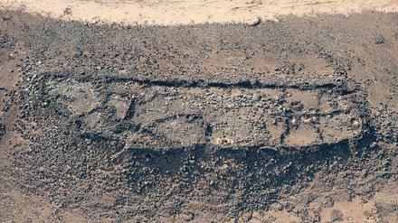 Zu sehen sind Spuren einer langgestreckten Siedlung mit Mauern, die auf einem Berg liegt, an dessen Hängen terrassierte Flächen zu erkennen sind.
