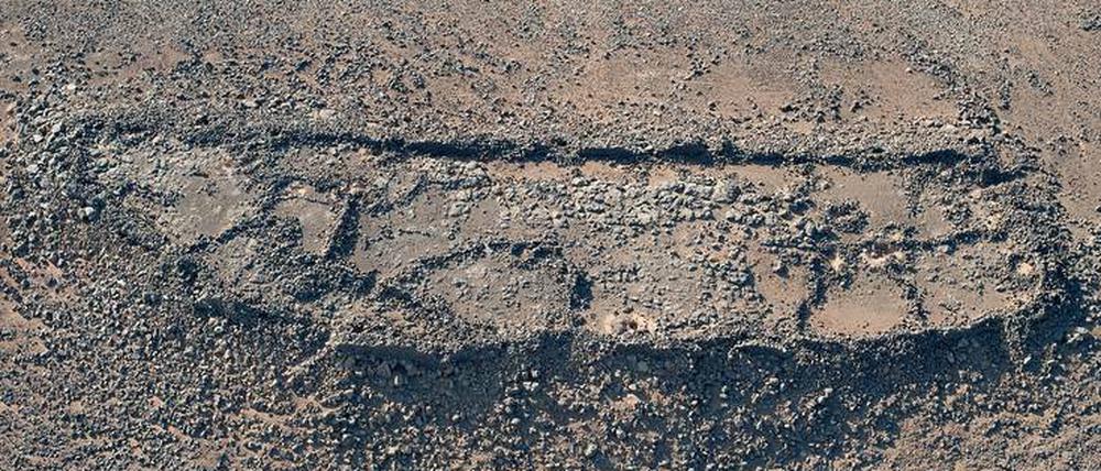 Zu sehen sind Spuren einer langgestreckten Siedlung mit Mauern, die auf einem Berg liegt, an dessen Hängen terrassierte Flächen zu erkennen sind.