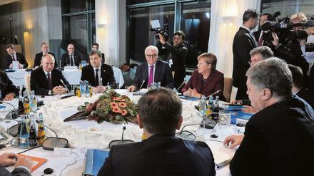 Krisengespräche am runden Tisch in Berlin, mit Wladimir Putin (l.) und Petro Poroschenko (vorn r.).