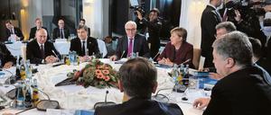 Krisengespräche am runden Tisch in Berlin, mit Wladimir Putin (l.) und Petro Poroschenko (vorn r.).