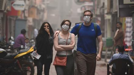 Fußgänger schützen sich in Indiens Hauptstadt Neu Delhi vor der seit Tagen anhaltenden extremen Luftverschmutzung. 
