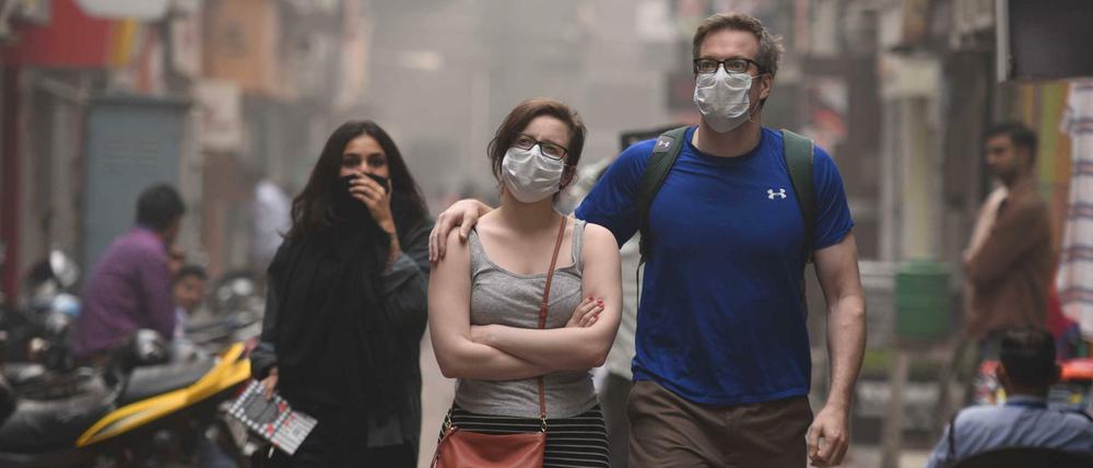 Fußgänger schützen sich in Indiens Hauptstadt Neu Delhi vor der seit Tagen anhaltenden extremen Luftverschmutzung.