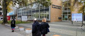 Passanten gehen an einem Gebäude vorbei und blicken in Richtung eines Plakats mit der Frage "Kennst du die schon?".