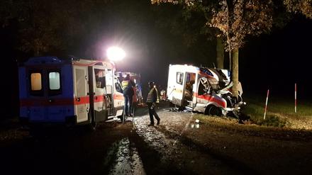 Rettungskräfte stehen am Donnerstag an einer Unfallstelle bei Langen (Niedersachsen), an der ein Rettungswagen gegen einen Straßenbaum geprallt ist.