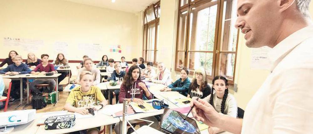 Mit Tablet vor der Klasse. Lehrer attestieren sich selbst gute Kompetenzen beim Umgang mit digitalen Medien. Experten zweifeln diese Selbsteinschätzung allerdings an.