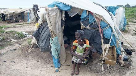 Hütte aus Plastikabfällen. Mama Rebecca lebt seit 2013 auf dem Flughafen der Hauptstadt Bangui. Mit einer ihrer Enkelinnen sitzt sie vor ihrer Behausung. 