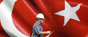 Ein türkischer Arbeiter vor einer riesigen türkischen Flagge. Erneut haben viele Staatsbedienstete ihre Jobs verloren. 