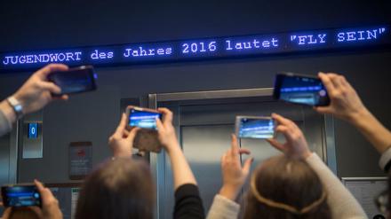 Die Worte "Fly sein" flimmern als "Jugendwort des Jahres" über den digitalen Newsticker eines Hotels in München.